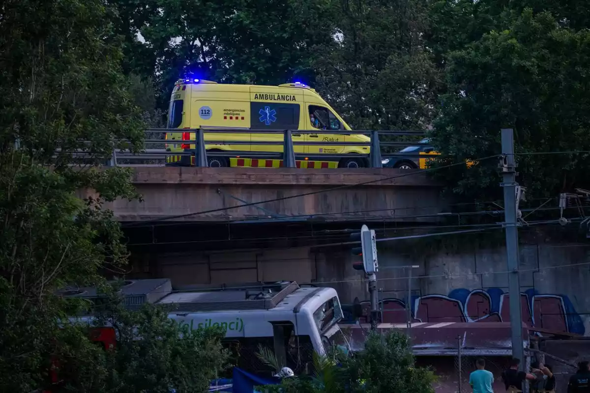 Imatge del tren de FGC accidentat sota el pont, on hi ha una ambulància