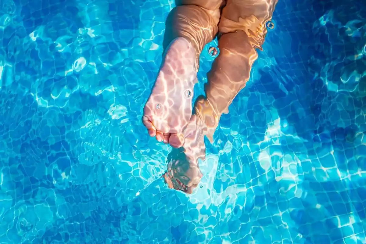 Imatge dels peus d'un nen nedant a una piscina