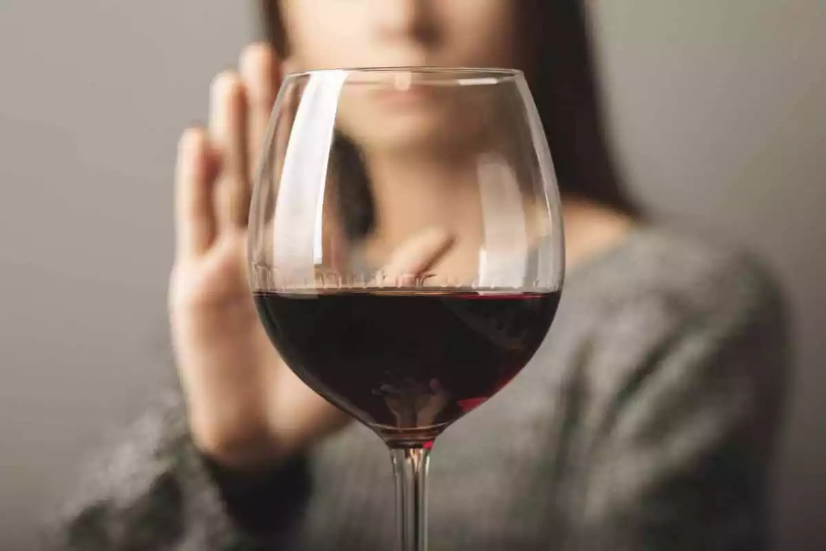 Imatge d'una noia negant amb la mà beure una copa de vi