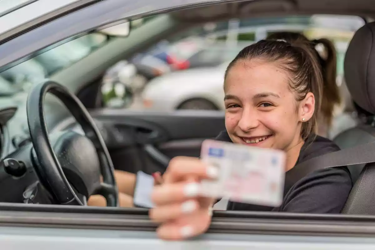Imatge d'una adolescent ensenyant el seu carnet de conduir.