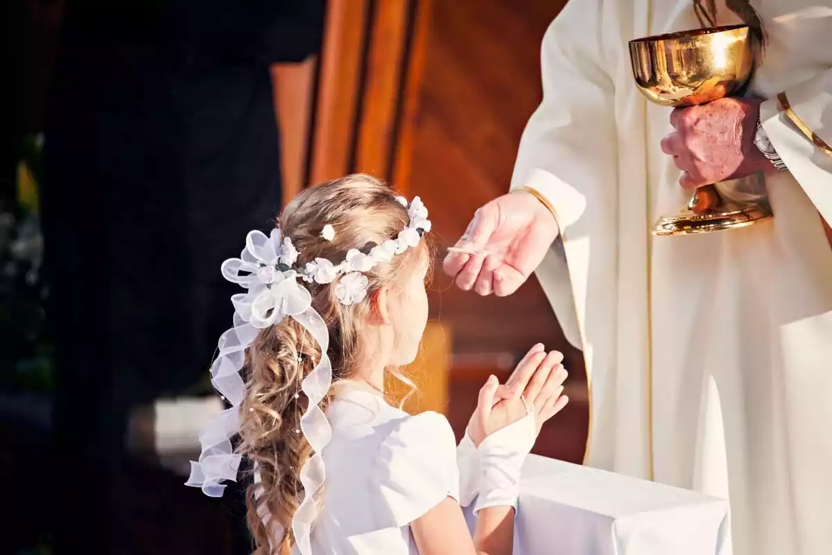 Imatge d'una nena agenollada davant del capellà a punt de fer la comunió