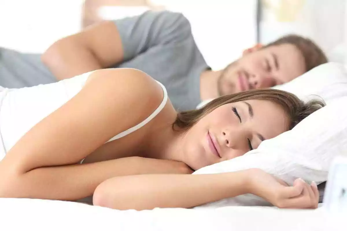 Imatge d'una parella dormint junts a un llit