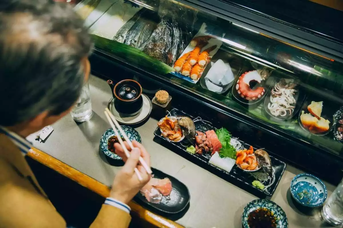 Un home menjant sushi amb bastonets