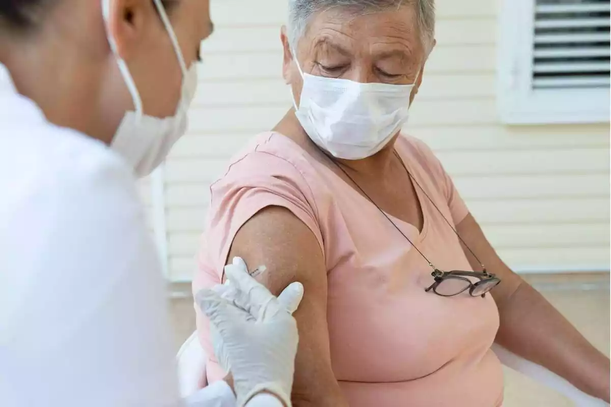 Una sanitària vacunant una dona