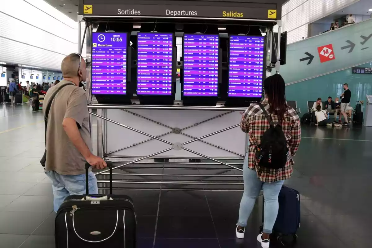 Dos usuaris mirant les pantalles informatives de la Terminal 2 de l'Aeroport del Prat