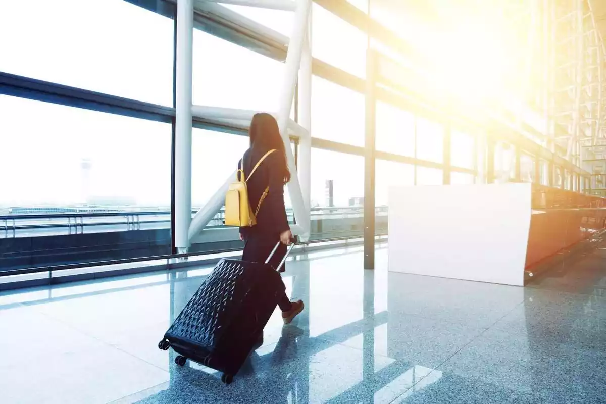 Foto d'una dona a un aeroport amb una maleta.