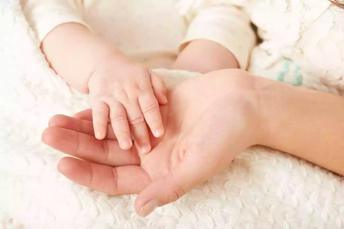 Imatge de la mà d'un bebè a sobre de la mà de la seva mare