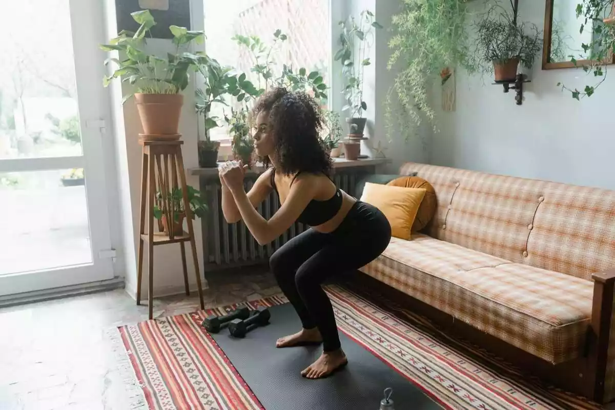 Imatge d'una noia practicant exercici física dins de casa