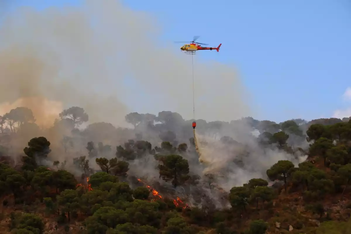 Un helicòpter llançant aigua a l'incendi de Castell d'Aro