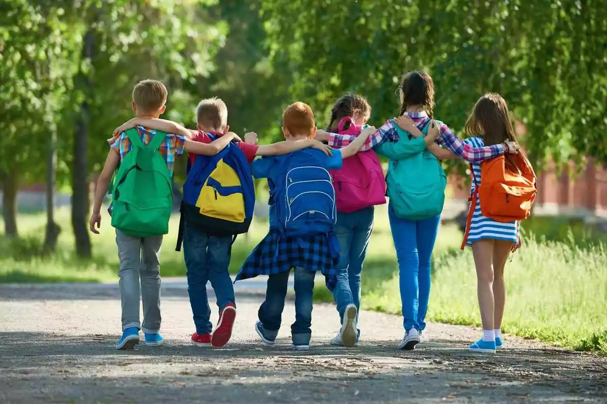 Foto d'un grup de nens d'esquena caminant i abraçats.
