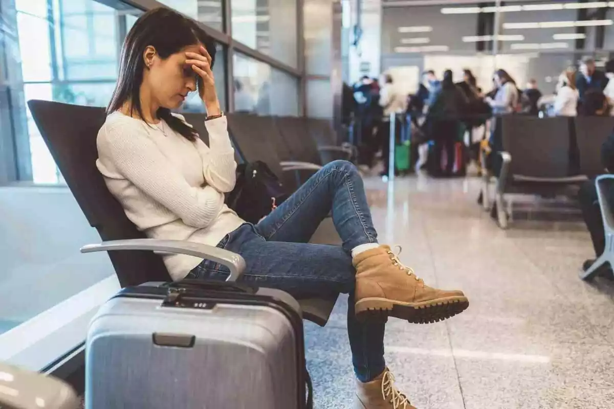 Foto d'una dona trista asseguda un aeroport.