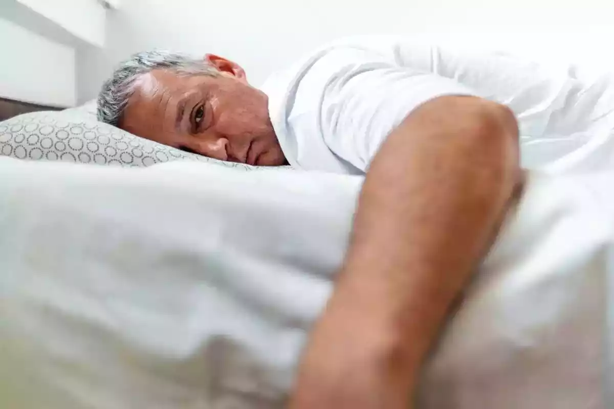 Foto home estirat al llit, no pot dormir