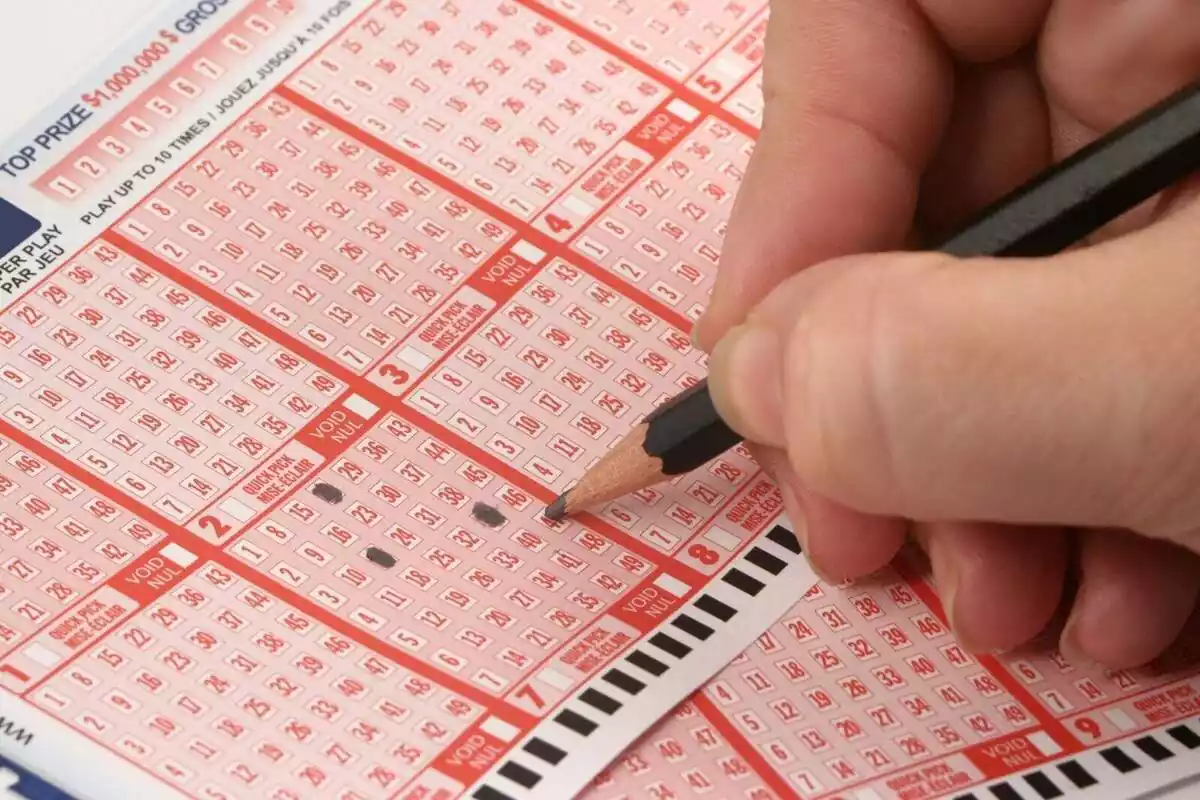 Primer pla d'una mà omplint una butlleta de la loteria