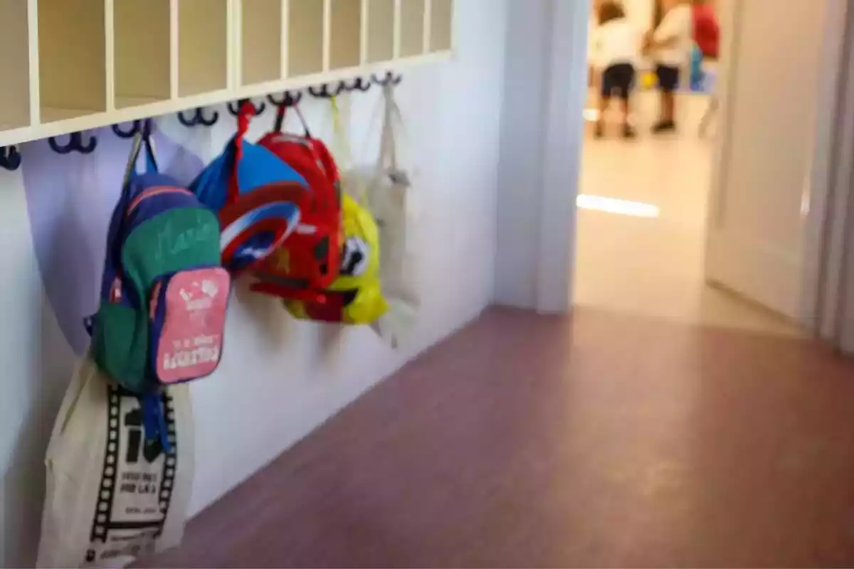 Foto d'un penjador d'una escola amb motxilles penjades