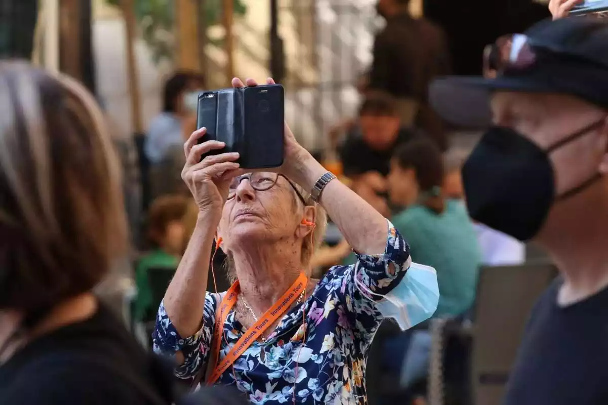 Foto d'una dona jubilada fent una foto amb el seu mòbil.