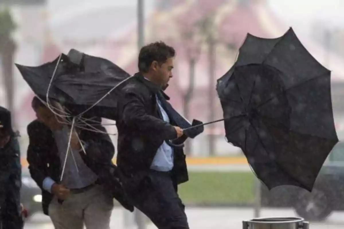Imatge d'un home subjectant el seu paraigües durant un temporal