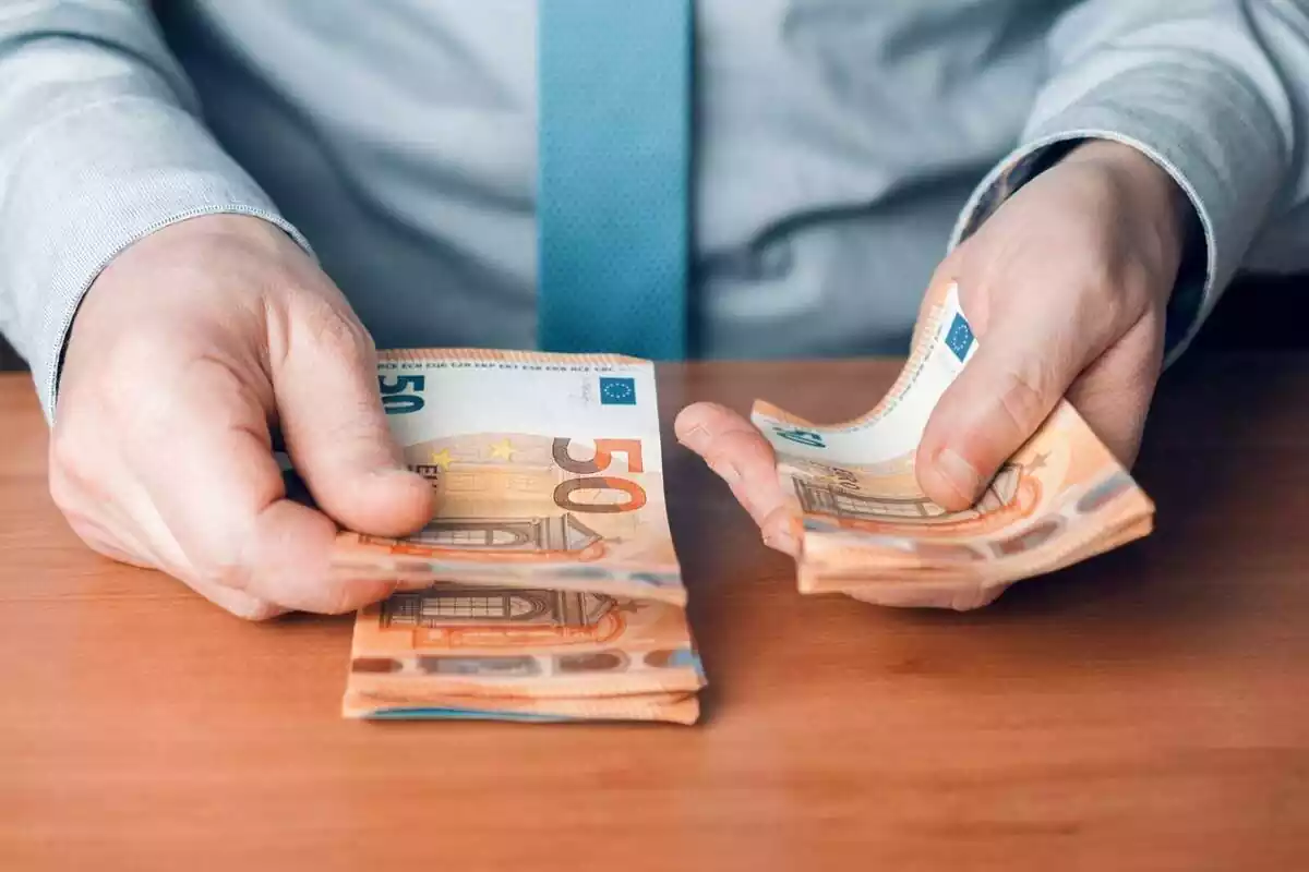 Foto d'un home comptant bitllets de cinquanta euros.