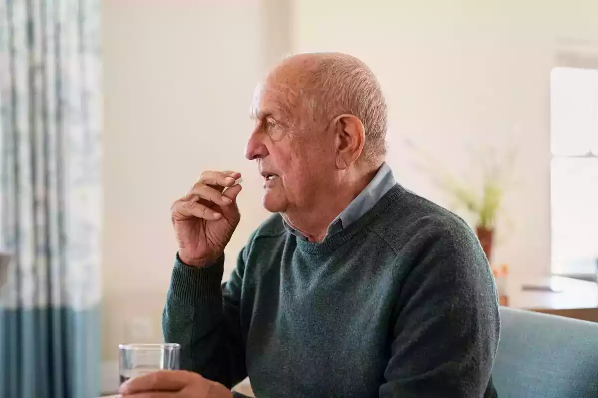 Foto d'un home vell prenent una pastilla
