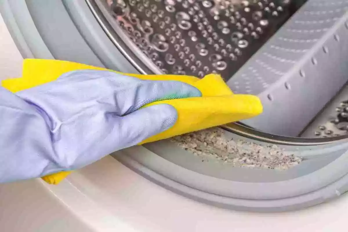 Foto d'una mà amb guant netejant una rentadora