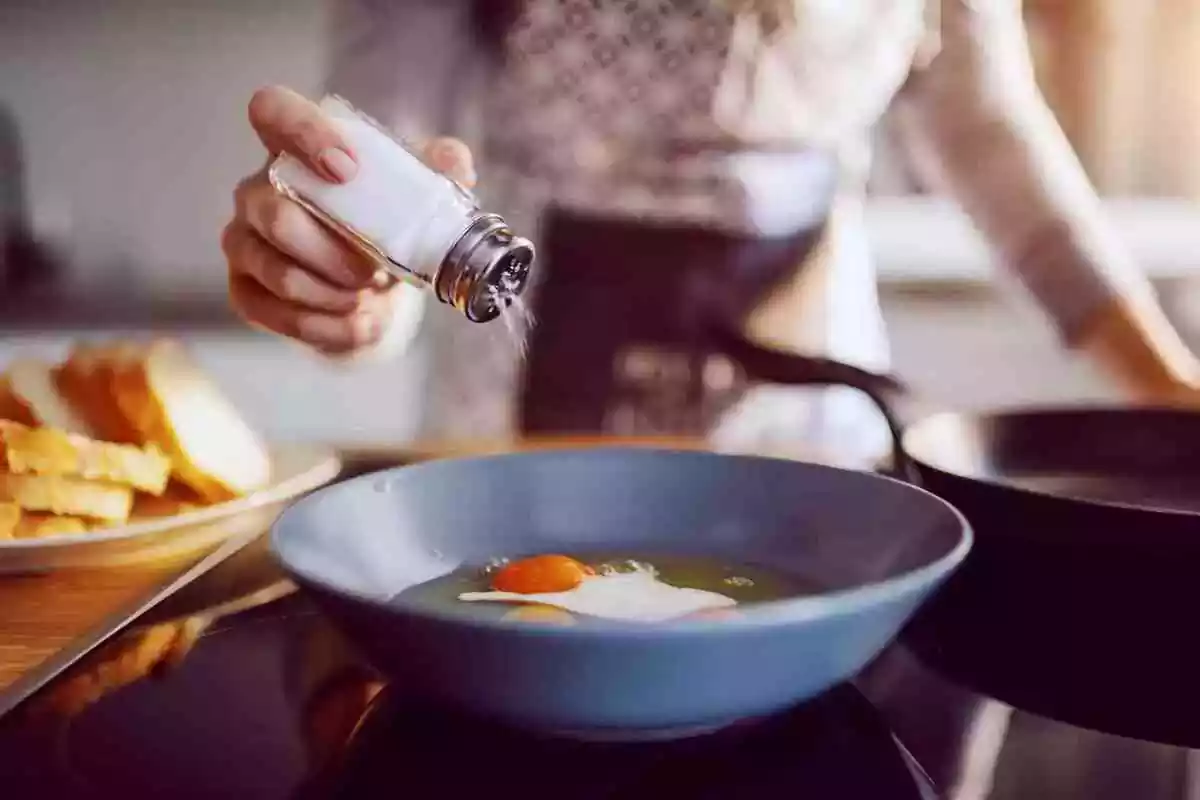 Foto d'una persona tirant sal a un plat