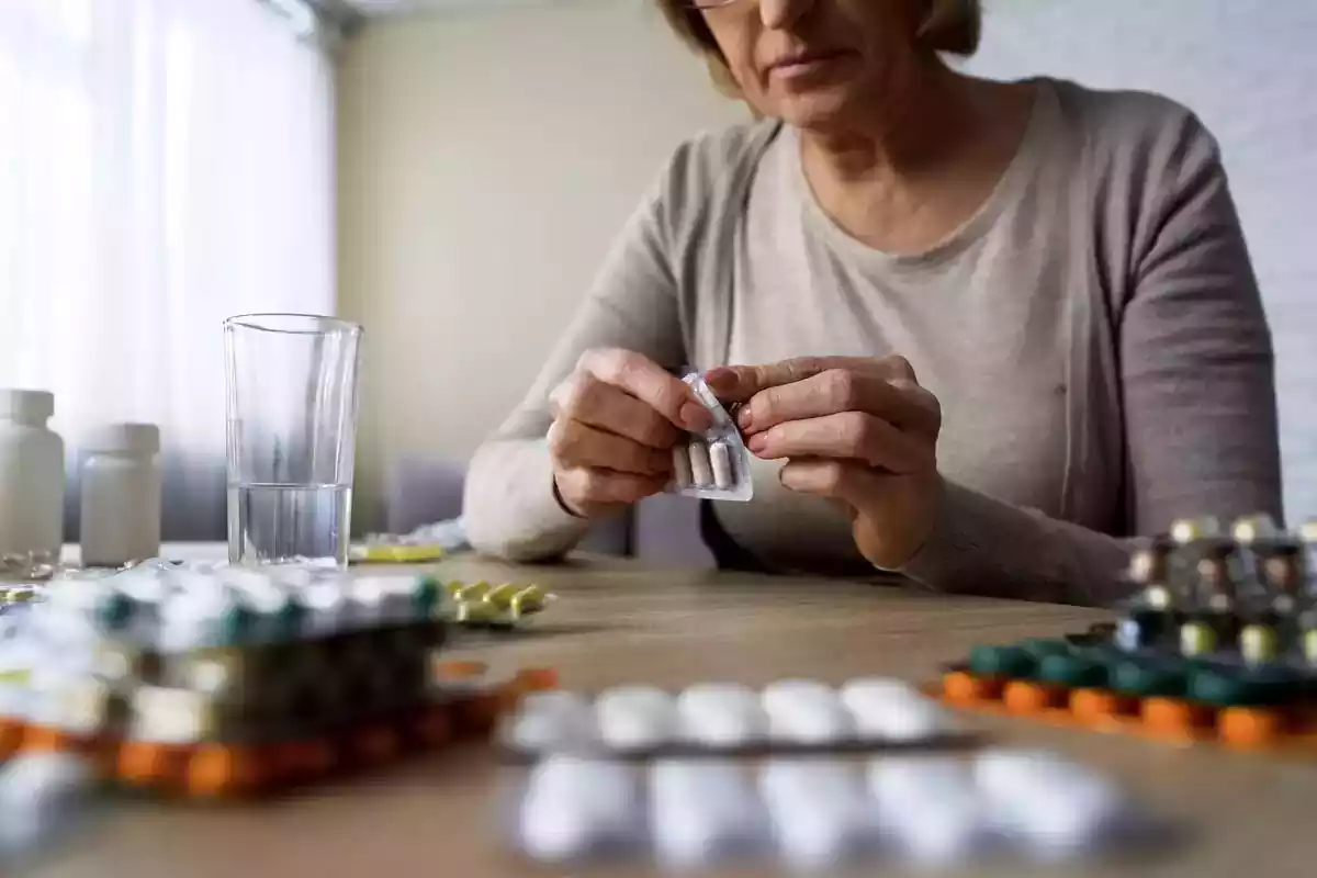 Foto d'una senyora amb pastilles sobre una taula