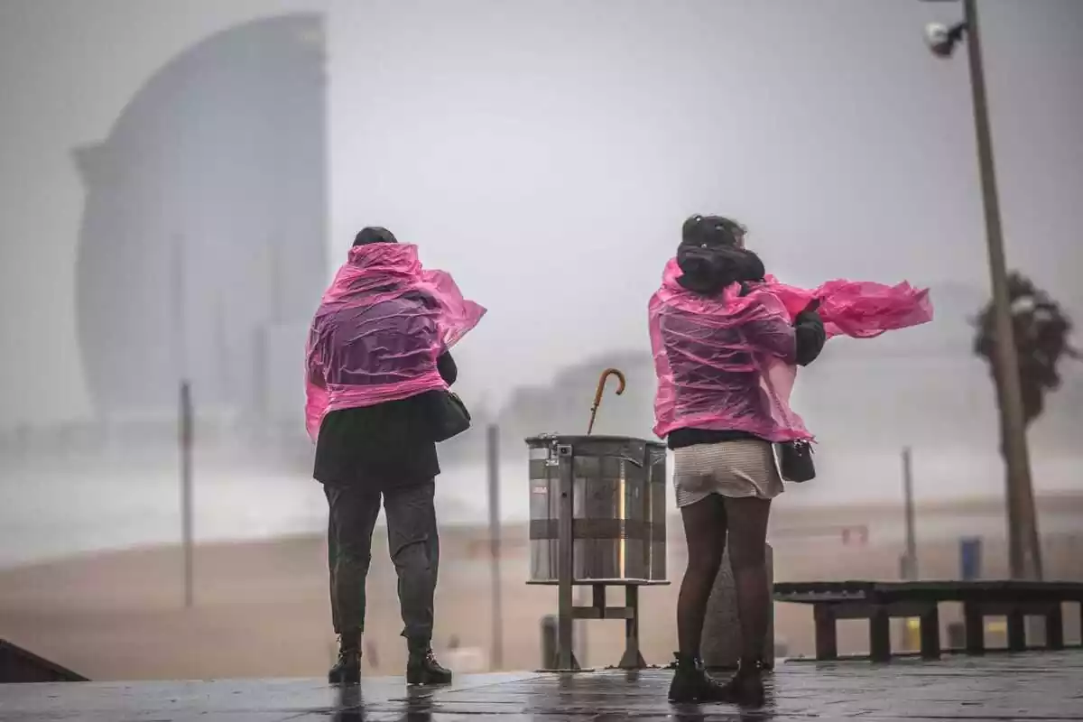 Imatge de dues dones a la Barceloneta sota la pluja.