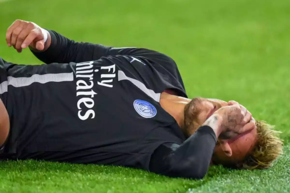 El jugador Neymar Jr. estirat al terra amb la ma a la cara