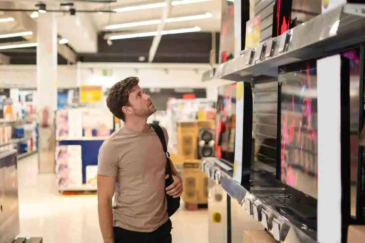 Foto d'un home comprant un televisor.
