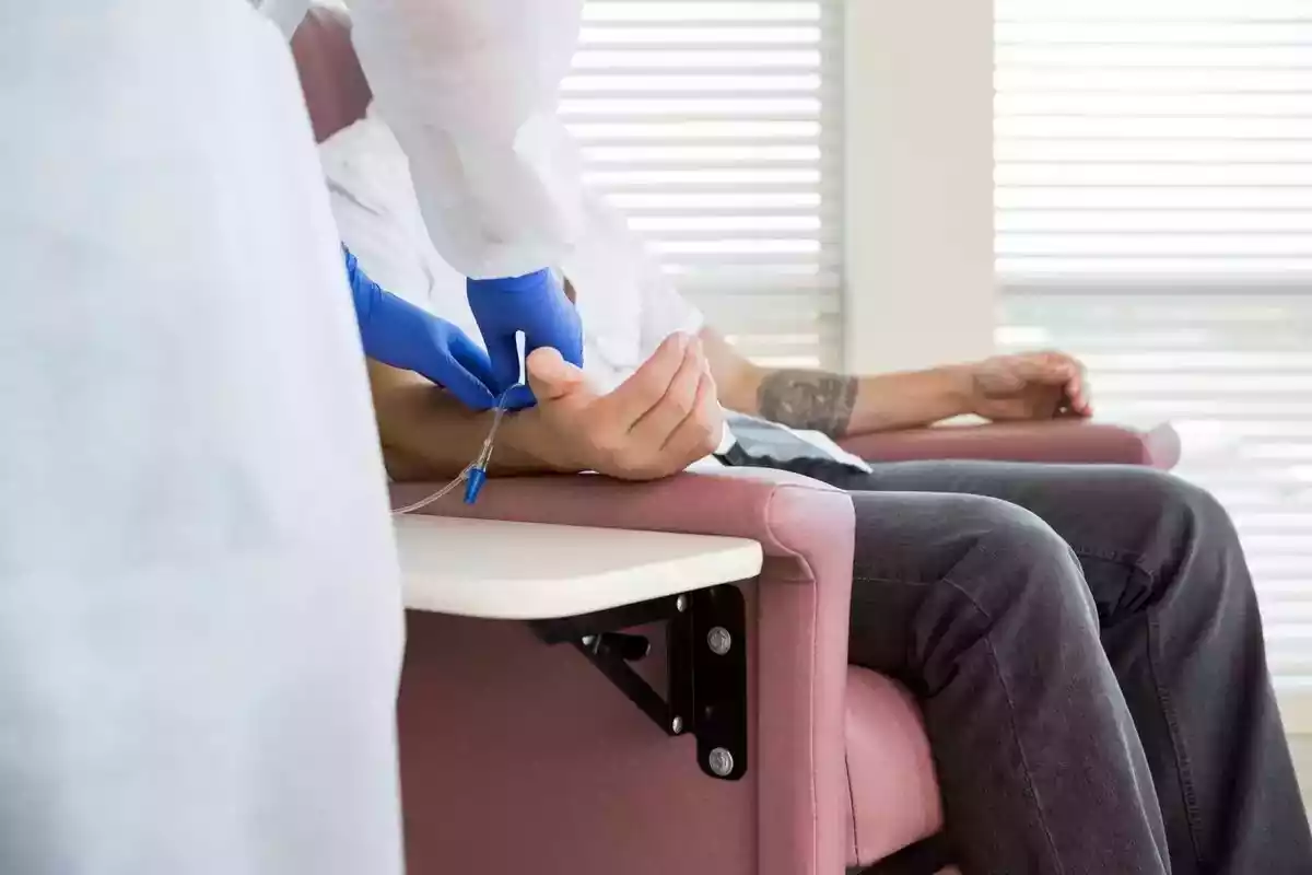 Foto d'una infermera posant una via al braç d'un paicent