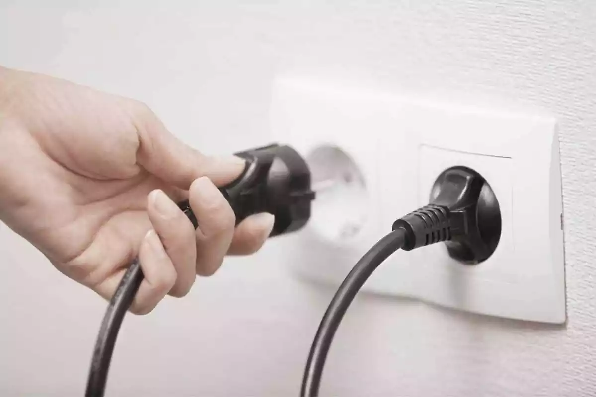 Imatge d'una persona endollant un cable al corrent elèctric