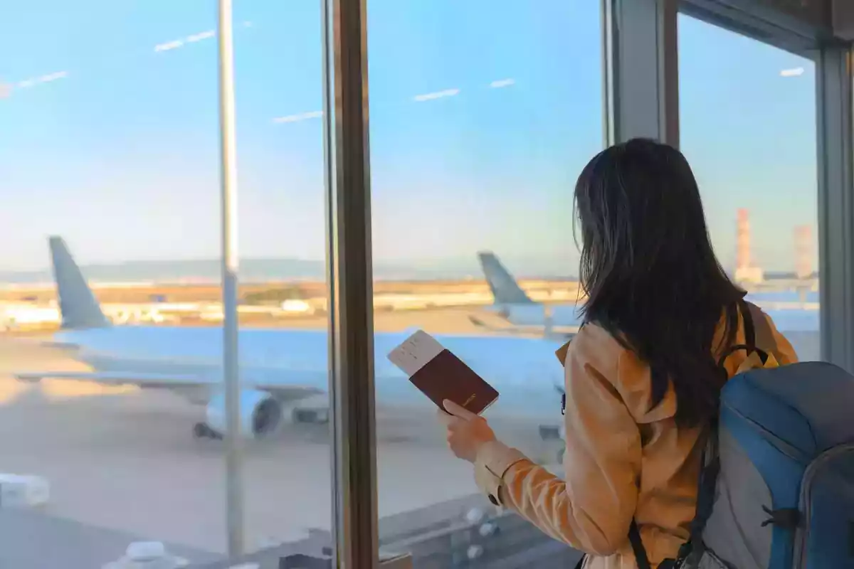 Foto d'una dona en un aeroport amb avions al fons