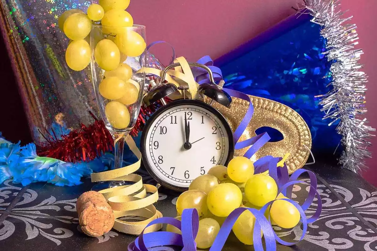 Imatge de la nit de Cap d'Any amb un rellotge, raïm, cotilló, etc.