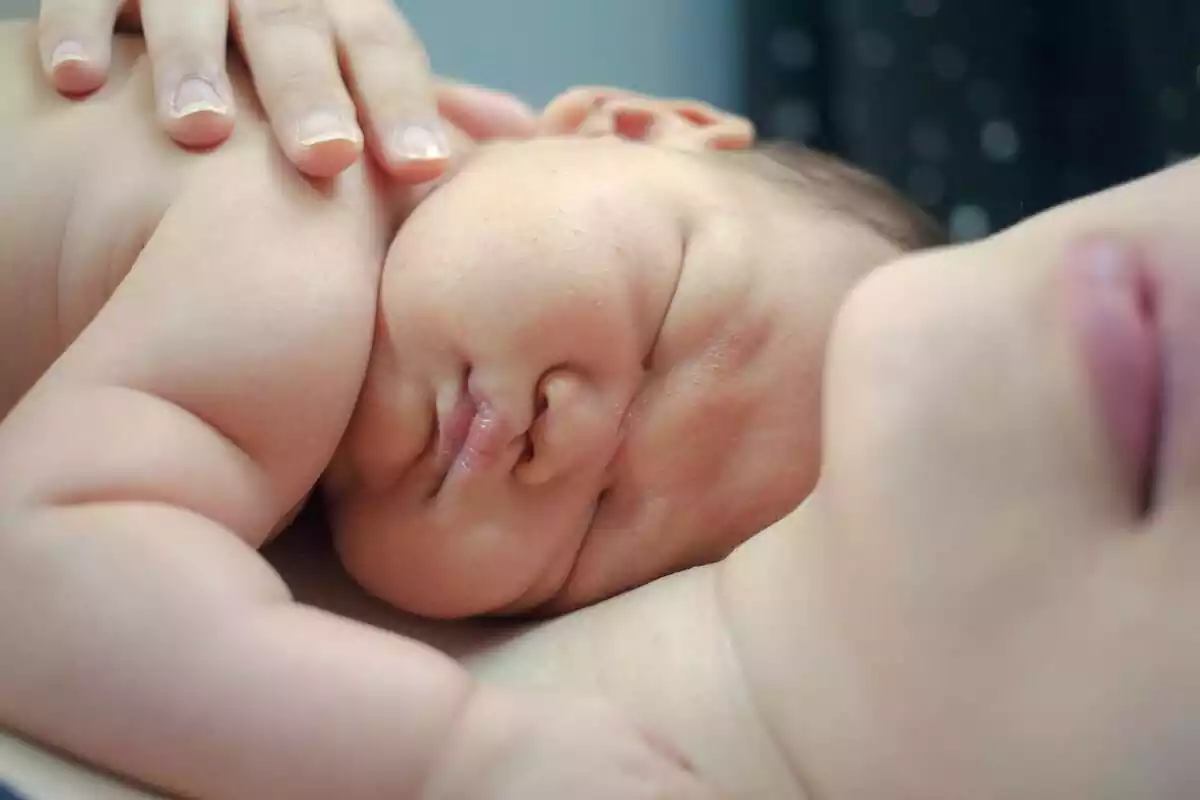 Imatge de nadó dormint sobre el pit de la mare que l'abraça