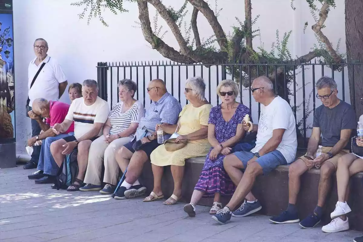 Imatge d'un grup de persones grans prenent l'ombra al carrer durant l'estiu
