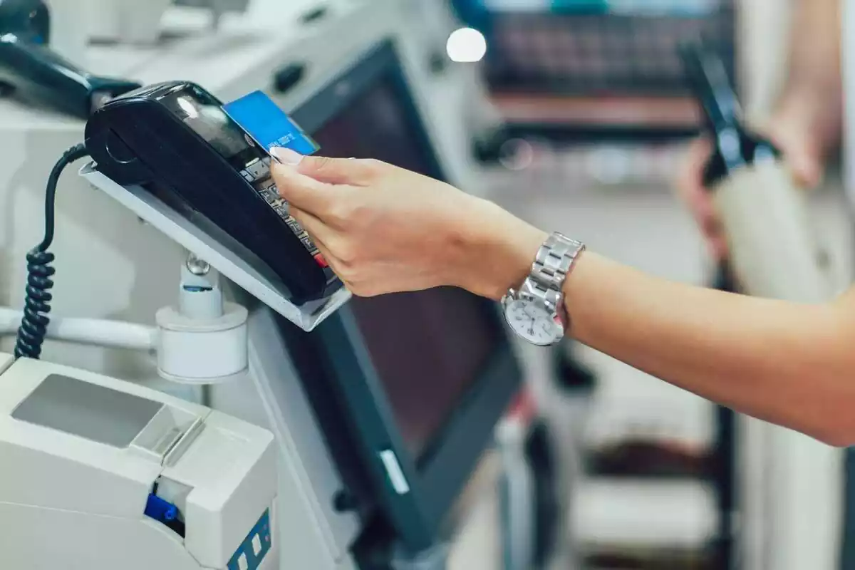 Imatge d'una persona pagant amb targeta en una caixa d'autopagament