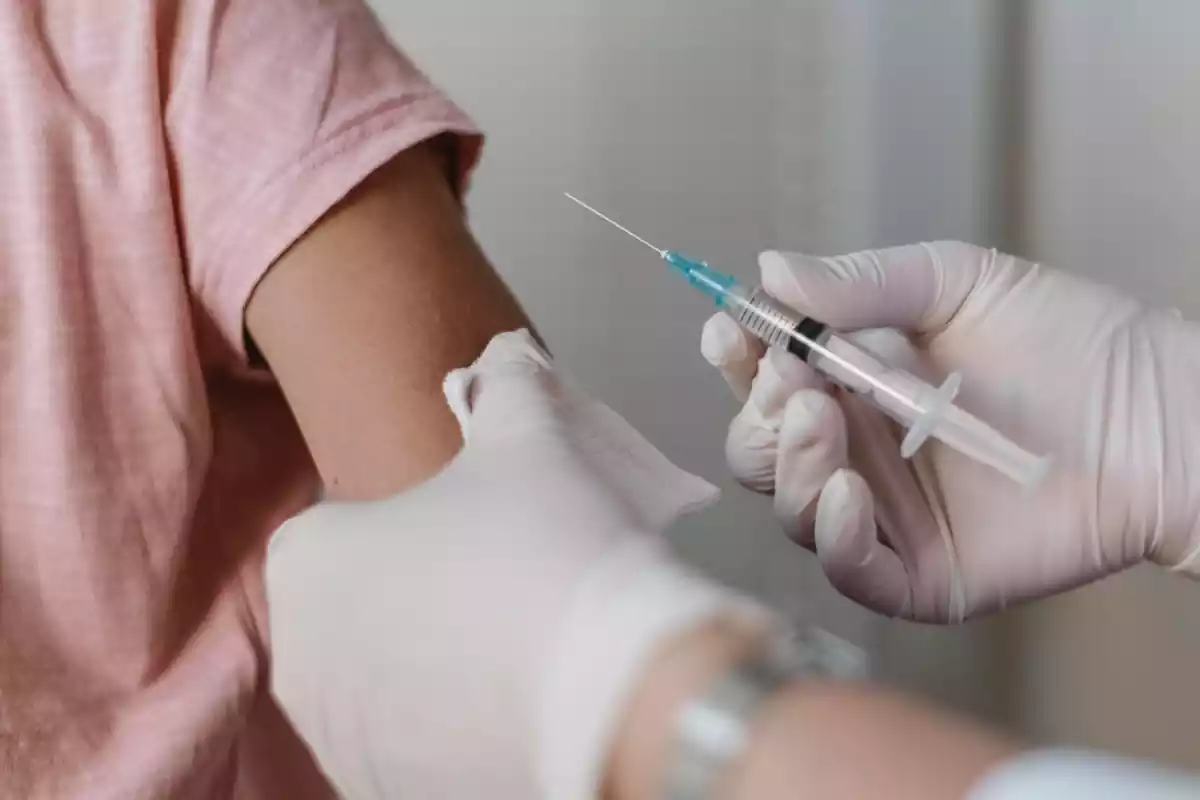 Imatge d'unes mans a punt de vacunar el braç d'un nen