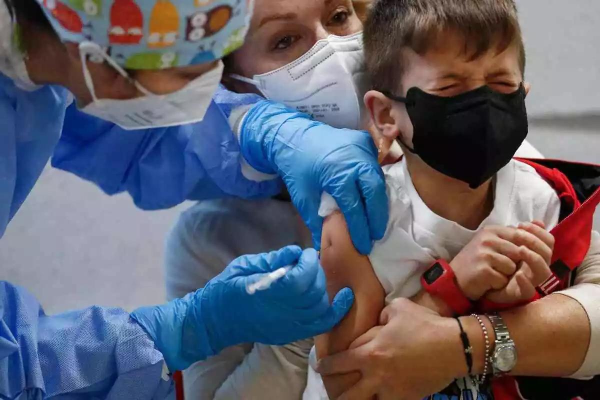 Un nen petit plorant mentre una infermera el vacuna