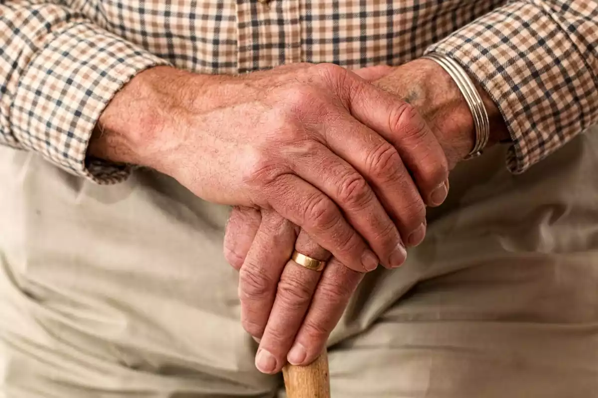Imatge de les mans d'un jubilat amb bastó