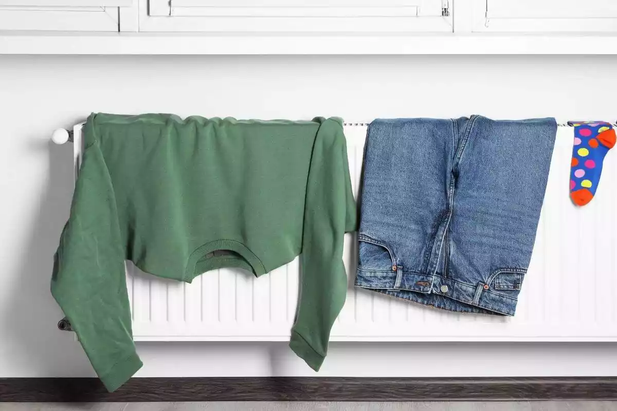 Imatge d'un jersei, pantalons i un mitjó damunt del radiador