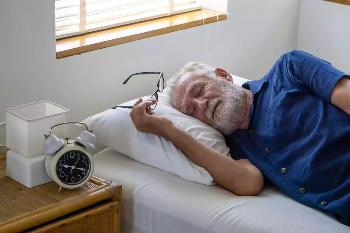 Imatge d'un senyor gran dormint a sobre d'un llit