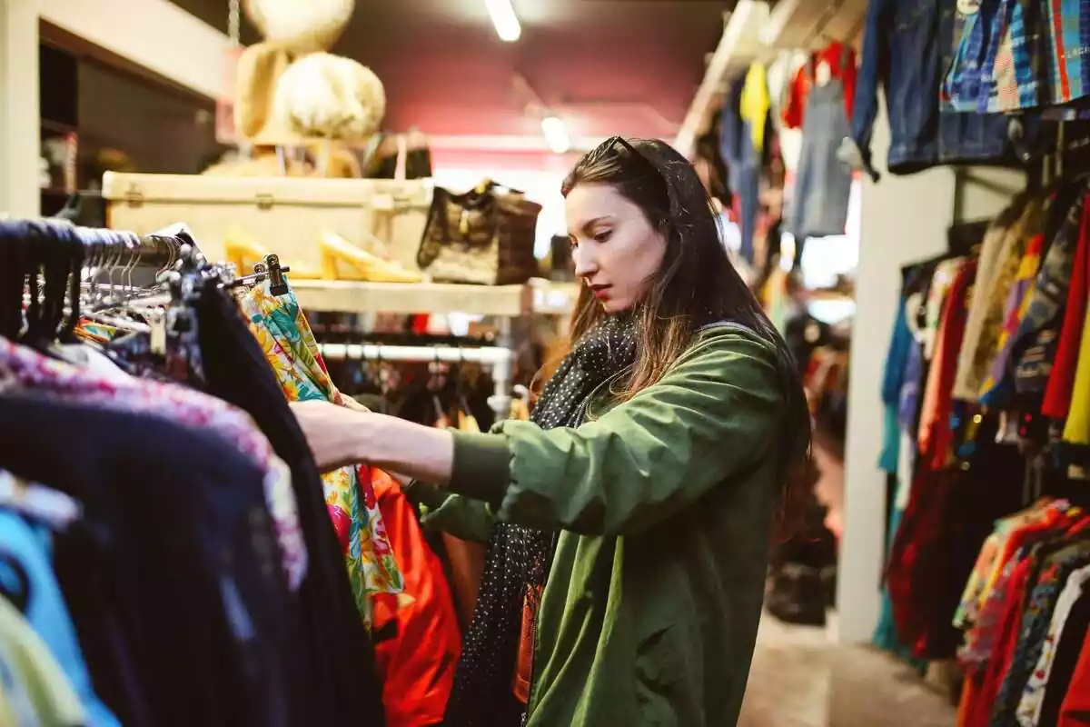 Imatge d'una jove comprant a una botiga de roba de segona mà