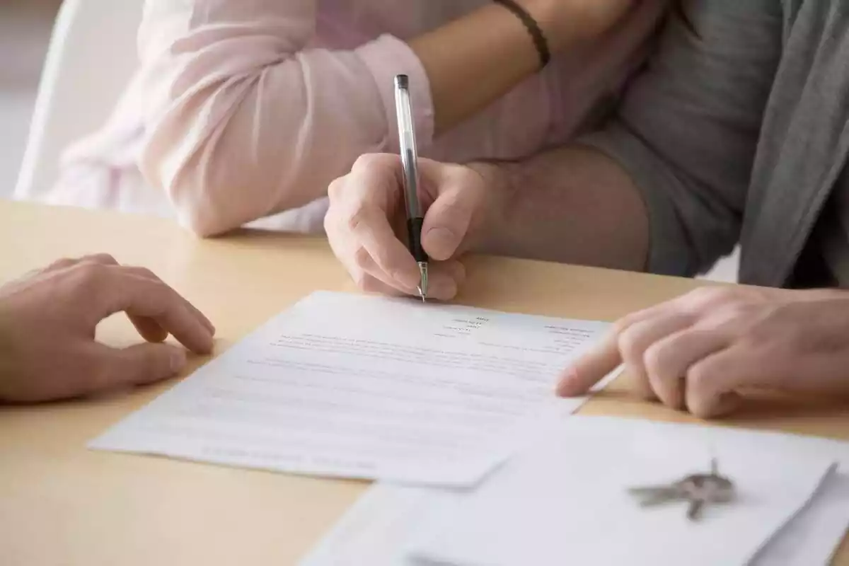 Foto d'una persona signant un document amb un bolígraf.