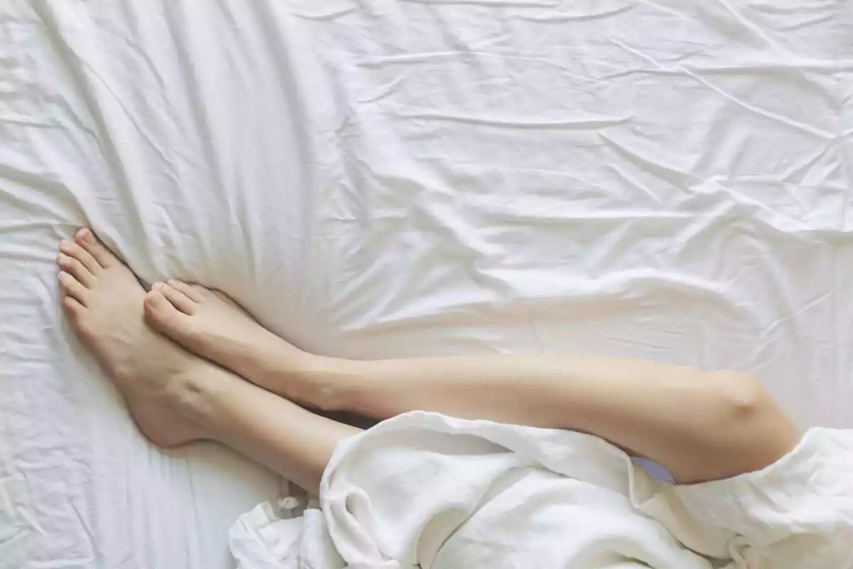 Imatge d'unes cames entre llençols blancs a un llit