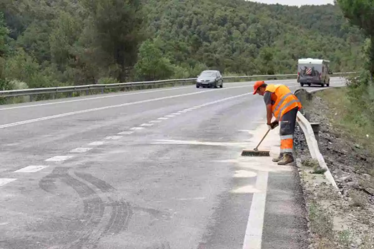 Imatge d'un operari netejant la carretera després d'un accident