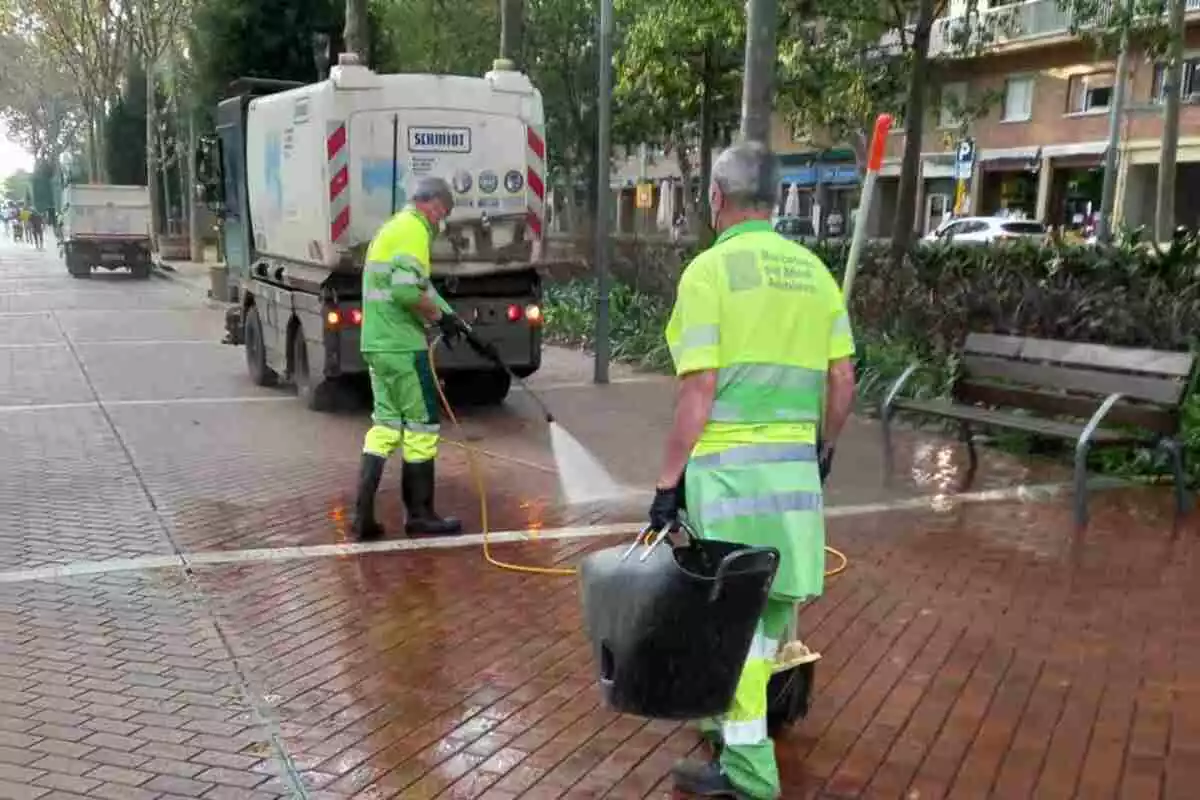 Imatge d'una màquina i dos operaris netejant el carrer