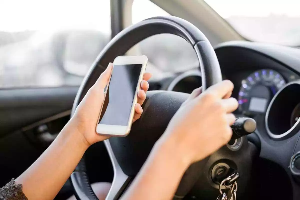 Imatge d'una persona conduint amb el mòbil