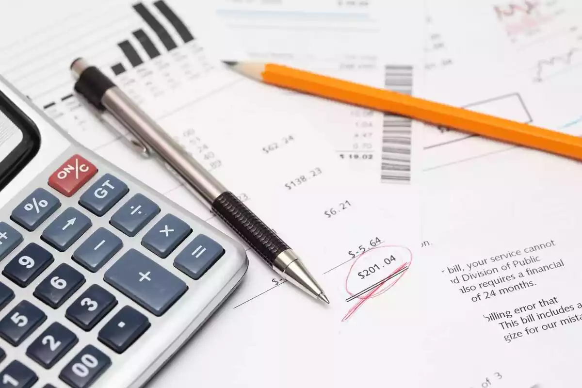 Imatge d'unes factures i una calculadora damunt de la taula