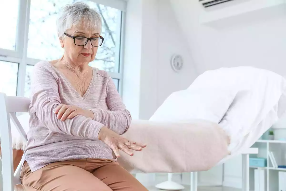 Anciana sentada estirant el braç