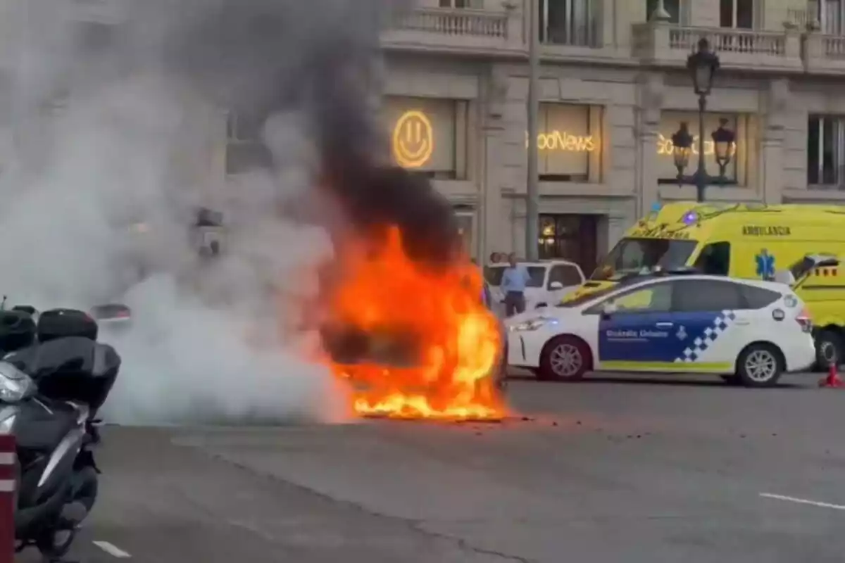 Foto d'un cotxe cremant a Plaça Francesc Macià de Barcelona.