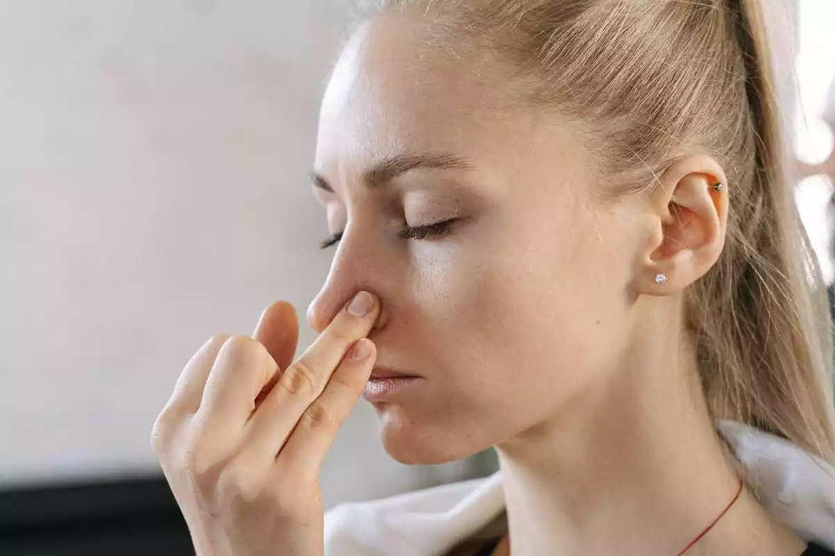 Imatge d'una dona apretant-se el nas